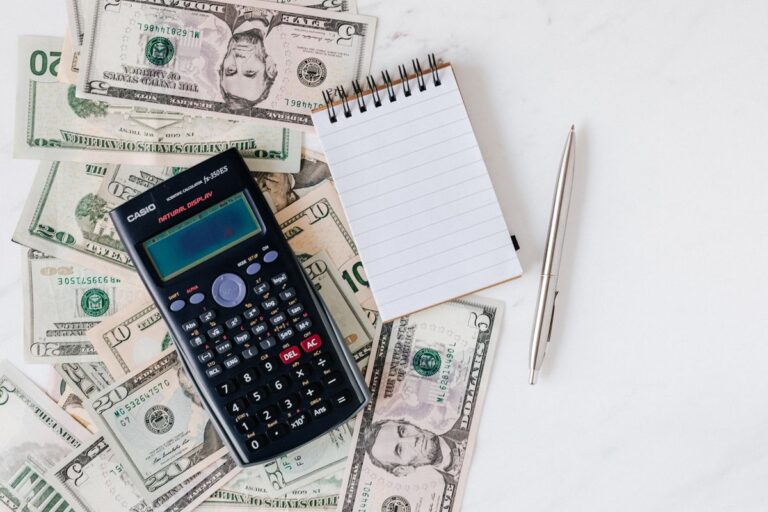 Calculator and notepad on top of bills