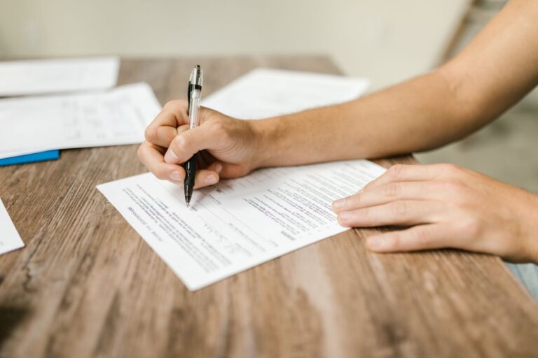 Person filling out an insurance form at a desk