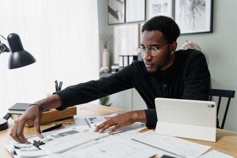 Professional reviewing payroll documents and a tablet at an office desk
